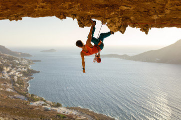 Male rock climber on challenging route going along ceiling in cave