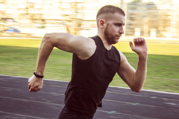 one caucasian male is doing a sprint start. running on the stadium on a rubber track. Track and field runner in sport uniform. energetic physical activities. outdoor exercise, healthy lifestyle