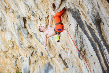 Young man climbing challenging route on overhanging cliff