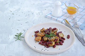 Warm salad of grilled Jerusalem artichoke and boiled red beans with olive oil and vinegar dressing on a white clay plate. Heathly food.