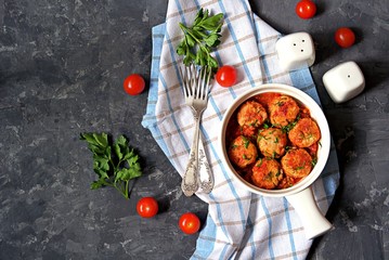 Fish meatballs in tomato sauce in a white ceramic pan on a dark concrete background. Top view. Seafood.