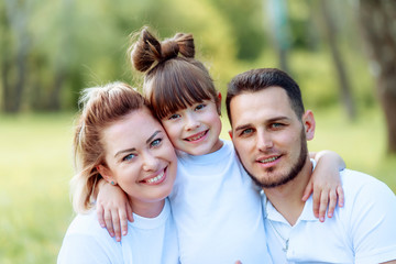 Fototapeta premium Happiness and harmony in family life. Happy family concept. Young mother and father with their daughter in the park.