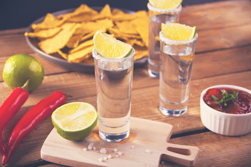 Tequila shot with lime and sea salt on wooden table