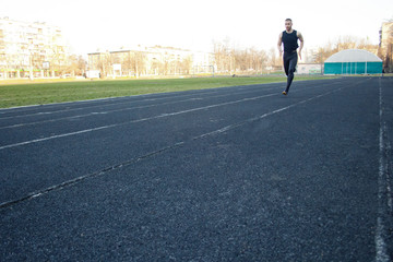 Obraz premium one caucasian male is doing a sprint start. running on the rubber track. Track and field runner in sport uniform. energetic physical activities. outdoor exercise, healthy lifestyle