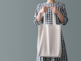 Blank canvas tote bag Eco product A woman in a plaid cotton dress is holding a reusable white shopping bag
