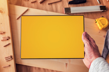 Carpenter holding digital tablet computer with blank mock up screen
