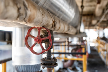 Worn steel catch in the workshop of a refinery with a red valve