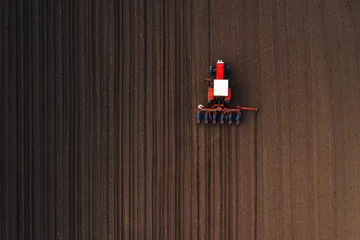 Schilderijen op glas Hoogste mening van tractor die graanzaad in gebied plant © Bits and Splits
