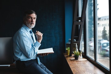 Concentrated at work. Focused mature businessman working and taking notes in his modern office.