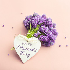 Spring vilet flowers and a heart shape card Happy Mother's Day on pastel pink.
