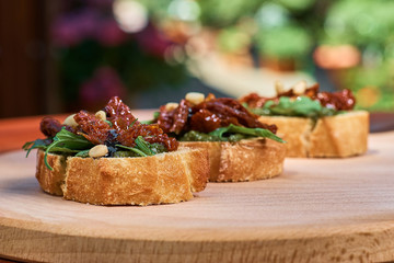 Wooden tray with tasty fresh Appetizing bruschettes on a wooden table, terrace, seafood, fish dish. Fresh food.