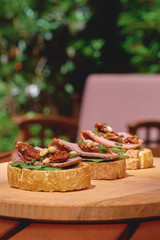 Wooden tray with tasty fresh Appetizing bruschettes on a wooden table, terrace, seafood, fish dish. Fresh food.