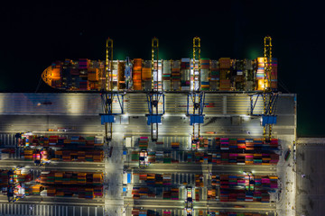 Aerial view. Container ships in the harbor with bridges Crane Operates export and import business at sea at night. Logistics and transportation