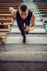 Caucasian man trains in running on the stairs. Track and field runner in sport uniform training outdoor. athlete, top view. step exercises. vertical