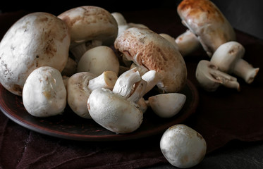 Fresh champignon mushrooms group on the table. Fresh vegetables mushrooms - the concept of healthy proper nutrition. Dark Food Photography
