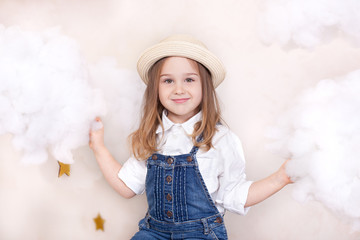 A smiling cute little girl flies in the sky with clouds and stars. Little astrologer Little traveler. The concept of preschool education of the child. Close-up face portrait