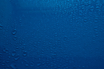 Drops of water on blue glass. Side view