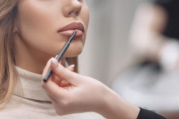 Young red-haired woman make-up artist puts make-up on the face of a beautiful blonde girl in a beauty salon. Concept of personal care and celebration preparation