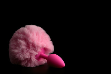 Pink anal tail plug isolated on black background.