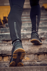 man trains in running on the stairs. Track and field runner in sport uniform training outdoor. athlete, below view. step exercises. vertical. pumped up shanks close up