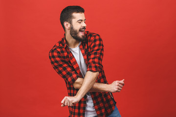 Photo of handsome young man dancing isolated over red wall background.
