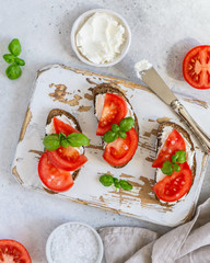 Toasted bread with tomatoes, ricotta (cream cheese), basil