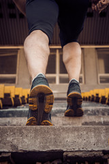 man trains in running on the stairs. Track and field runner in sport uniform training outdoor. athlete, below view. step exercises. vertical. pumped up shanks close up