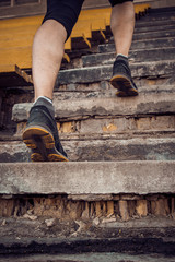 man trains in running on the stairs. Track and field runner in sport uniform training outdoor. athlete, below view. step exercises. vertical. pumped up shanks close up