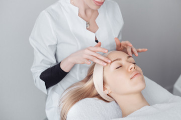 Unknown masseuse beautician doing a face massage to her client a beautiful young woman. Skin care concept