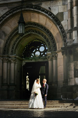 happy gorgeous bride and stylish handsome groom  on background of an amazing building church in the city