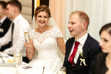 happy gorgeous bride and stylish groom cheering and toasting with guests and family at luxury wedding reception, emotional moment