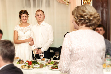 happy gorgeous bride and stylish groom cheering and toasting with guests and family at luxury wedding reception, emotional moment