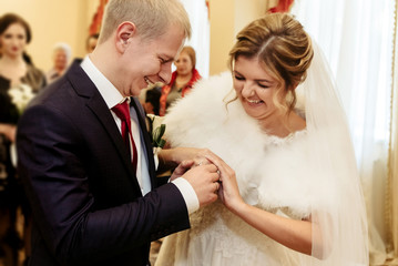 happy gorgeous bride and stylish groom exchanging wedding rings and laughing, emotional moment, official ceremony