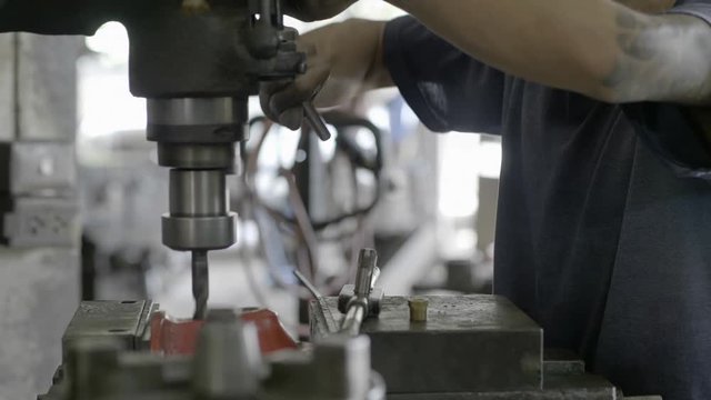Workers are working drilling machine, Drilling thick steel in the industrial factory. Slow motion..