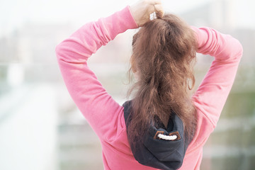 young woman in a pink suit getting ready for sports training in the early summer morning in the city center. the view from the back overcame into the distance.