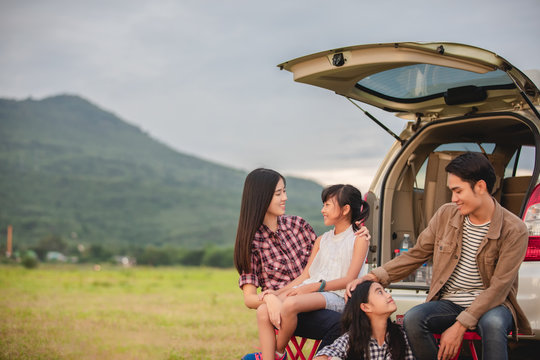 Happy little girl  with asian family sitting in the car for enjoying road trip and summer vacation in camper van