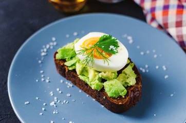 Healthy healthy snack (breakfast) - sandwich with avocado and egg on a gray plate.