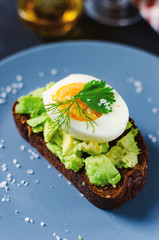 Healthy healthy snack (breakfast) - sandwich with avocado and egg on a gray plate.