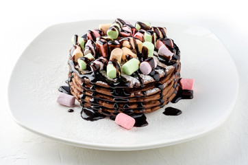 Chocolate pancakes with marshmallows and chocolate sauce.
