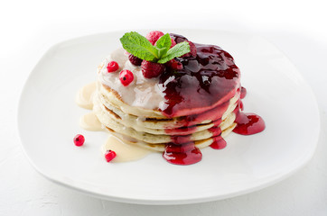 A stack of pancakes with condensed milk and berry jam.