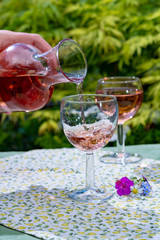 Wine carafe and glasses with cold rose wine and wild flowers in summer sunny day