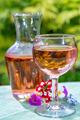 Wine carafe and glass with cold rose wine and wild flowers in summer sunny day