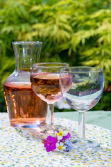 Wine carafe and glasses with cold rose wine and wild flowers in summer sunny day