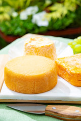 French cheeses collection, Riche de Saveurs, Langres and Le peche des bons peres cheeses served on white marble plate outdoor in green garden