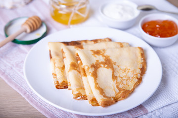 Traditional Russian pancakes with honey, sour cream and jam. Shrovetide. Maslenitsa week. Selective focus, close-up.