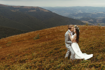 gorgeous bride and stylish groom hugging,  boho wedding couple, luxury ceremony at mountains with amazing view, space for text