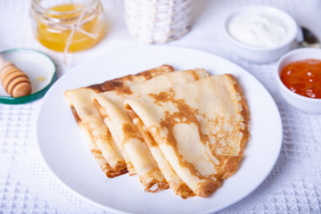 Traditional Russian pancakes with honey, sour cream and jam. Shrovetide. Maslenitsa week. Selective focus, close-up.