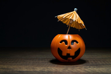 Orange Pumpkin Halloween with umbrella on wooden table in black background