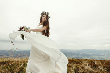 Fototapeta na wymiar gorgeous bride dancing and having fun holding dress, boho wedding, luxury ceremony at mountains
