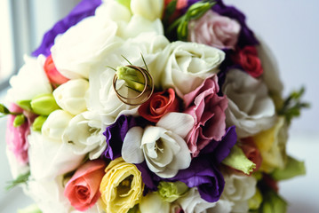 golden wedding rings on beautiful colorful bridal bouquet